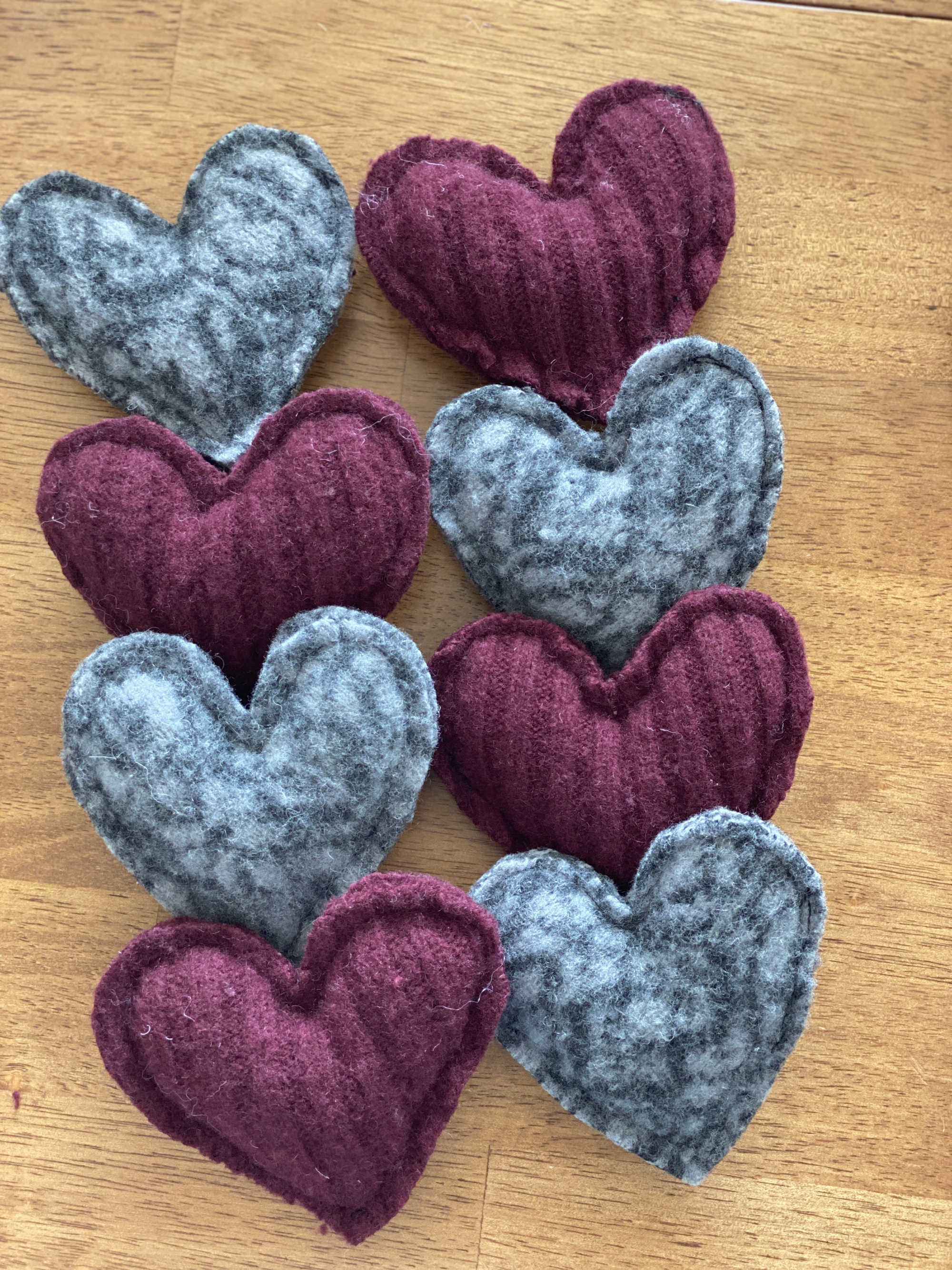 Two rows of stuffed grey and maroon felted hearts.
